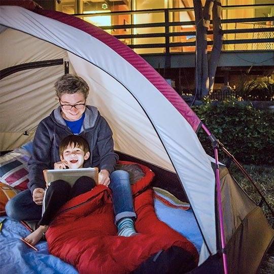 两个男孩在自家后院的帐篷里用平板电脑通过固定无线传输内容