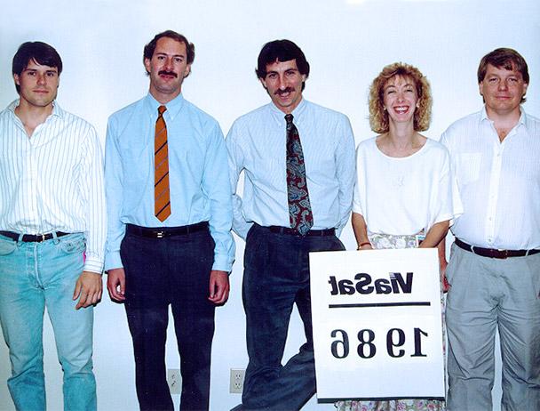 Founders Mark Dankberg, 史蒂夫·哈特和马克·米勒加上两名菲律宾bg视讯官网的员工站在一个写着“Viasat 1986”的牌子后面